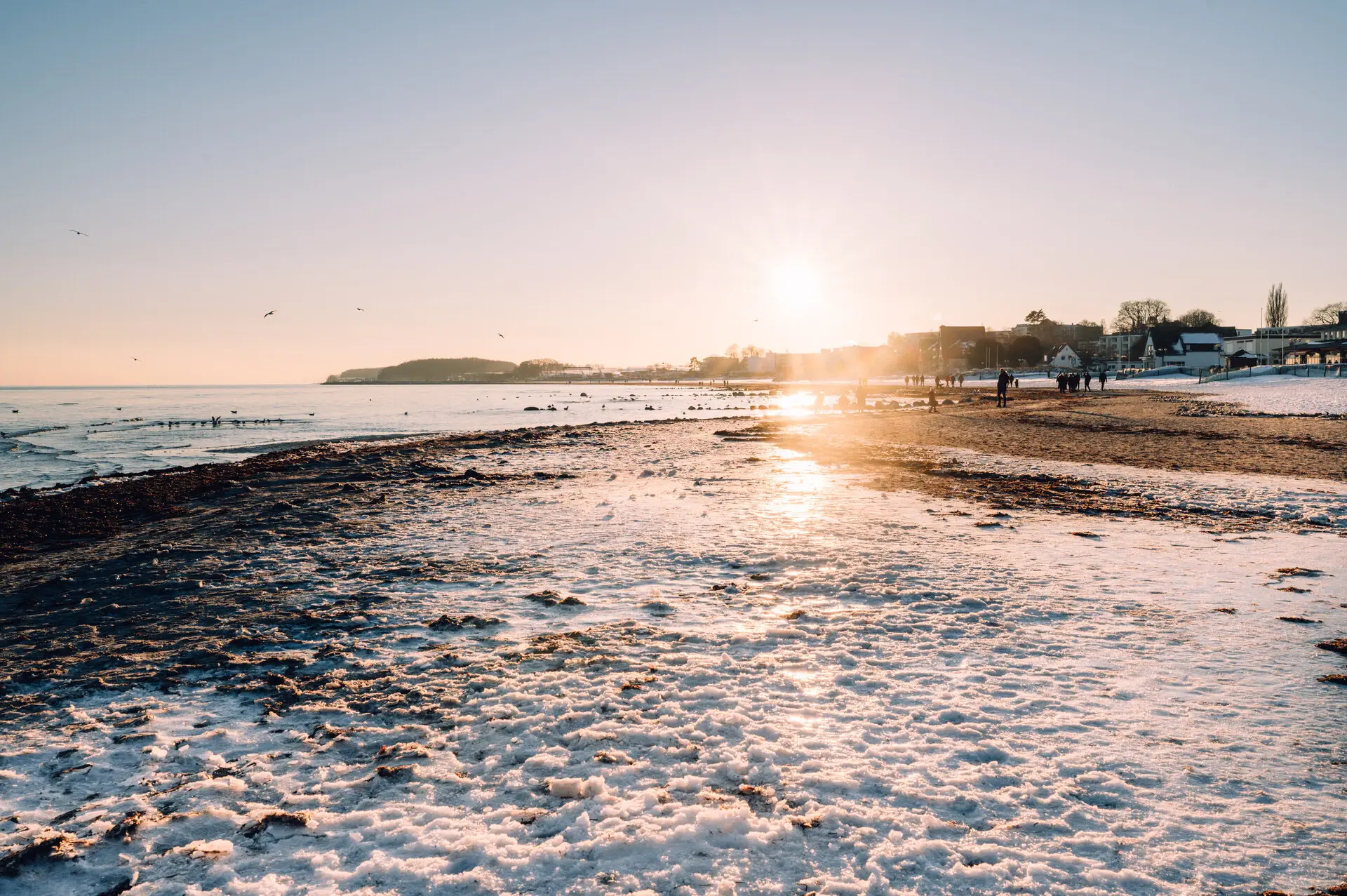 Seebrücke Grömitz Ein ruhiger schneebedeckter Strand in der Morgensonne.