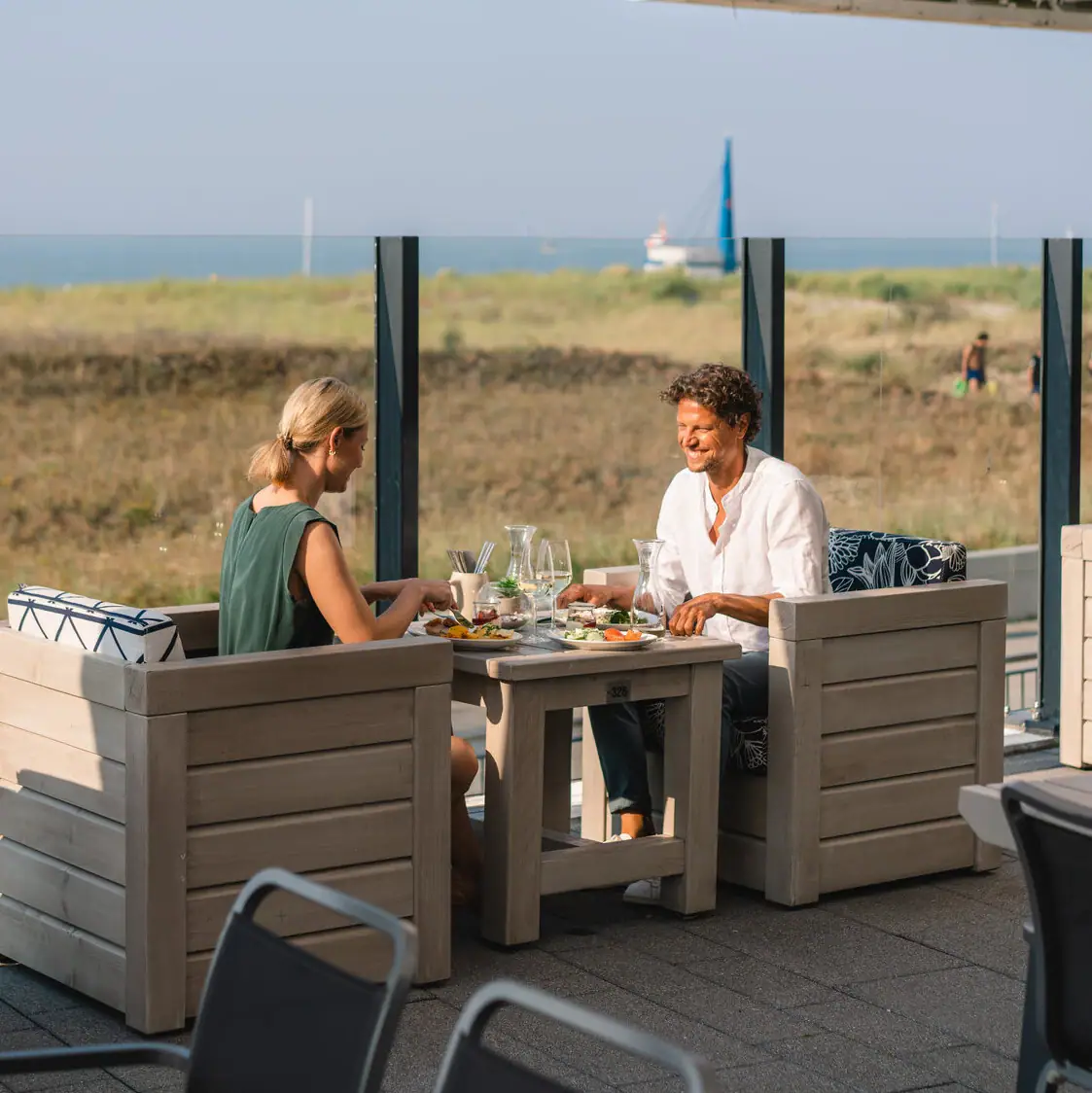 Terrasse aja Warnemünde Eine Gruppe von Menschen sitzt an einem Tisch im Freien.