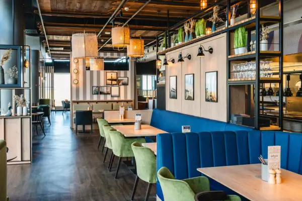 Restaurant im aja Warnemünde Ein Restaurant mit Tischen und Stühlen.