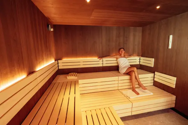 Sauna Eine Frau in einem Handtuch sitzt auf einer Bank in einer Sauna.