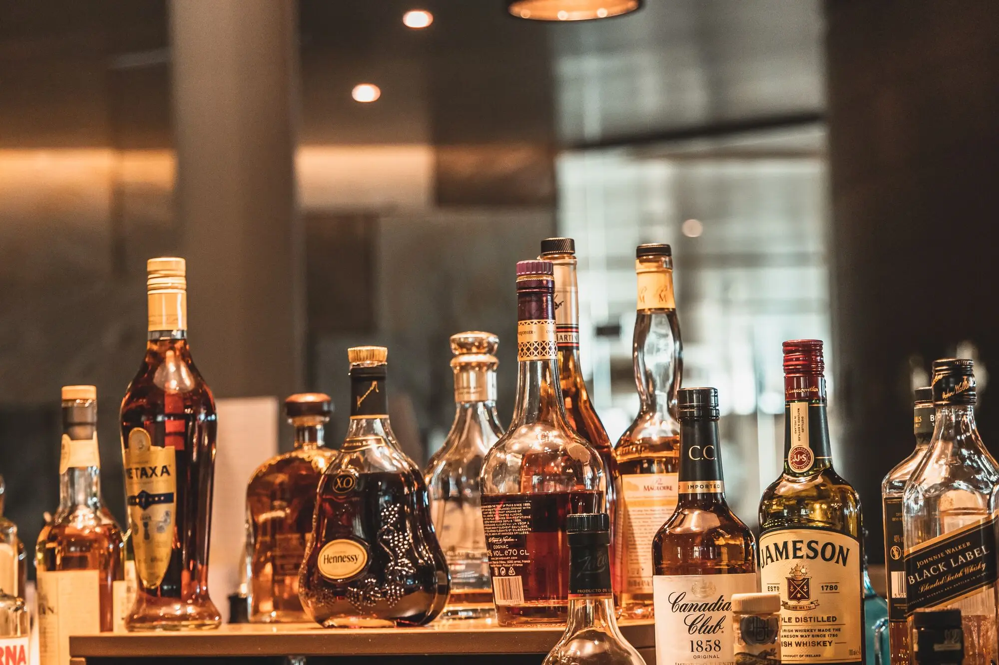 Eine Auswahl an Alkoholflaschen auf einer Theke, darunter Whisky und Liköre.