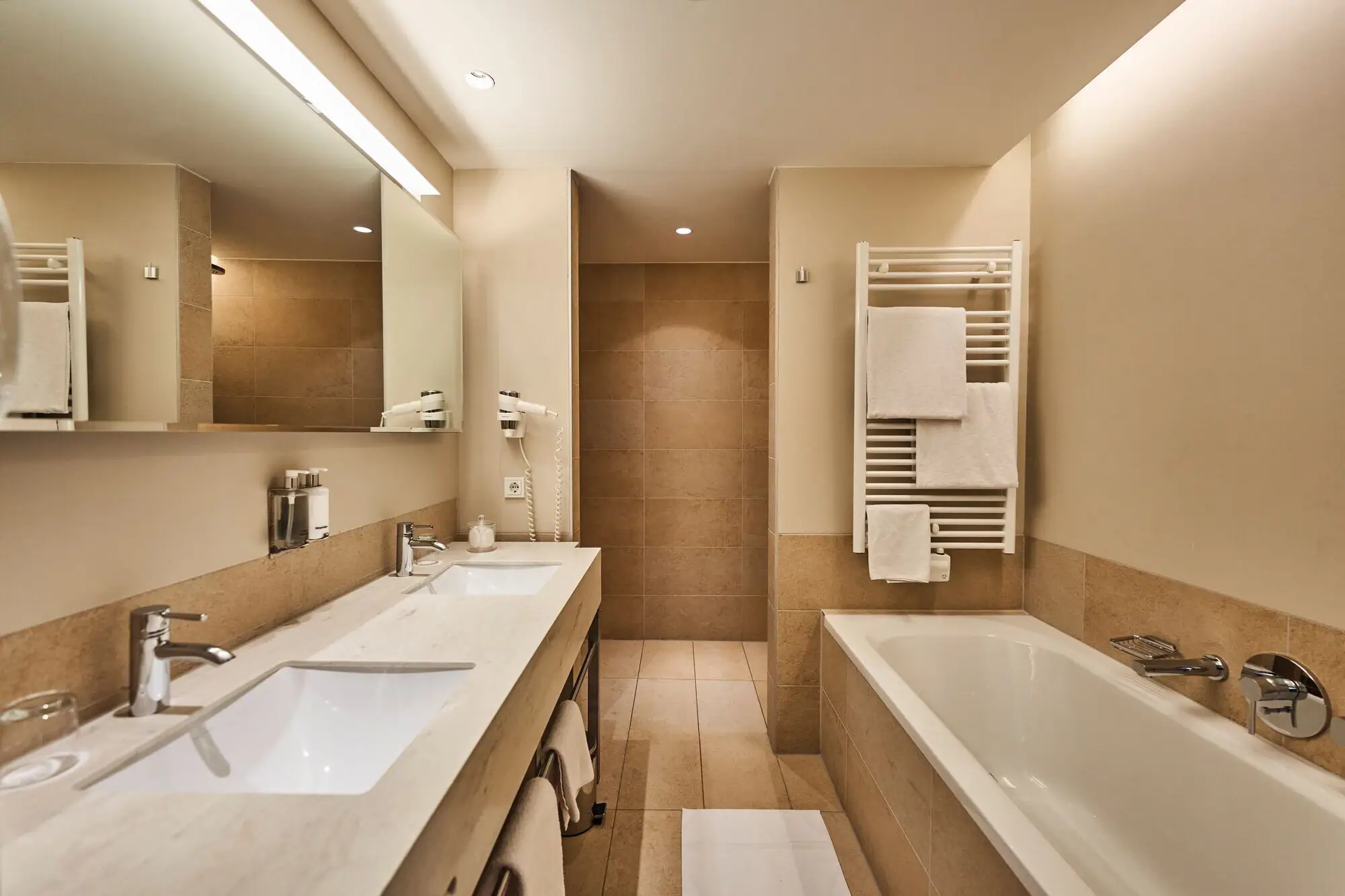 Suite Badezimmer Badezimmer mit Badewanne und Waschbecken, ausgestattet mit Armaturen und Fliesen.