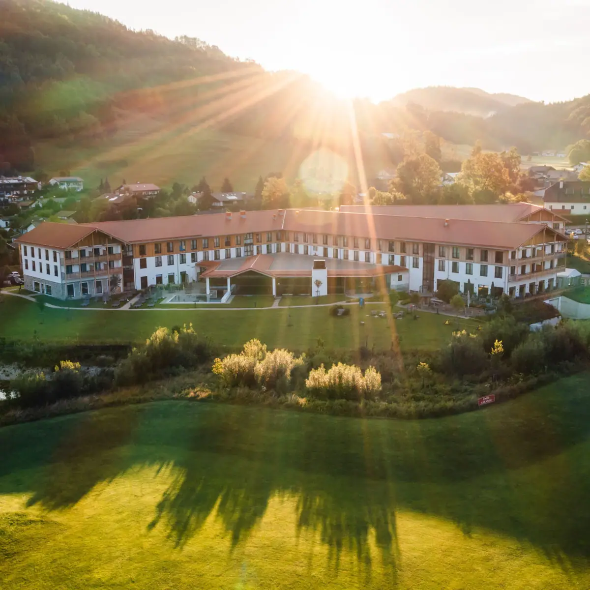 aja Ruhpolding Ein großes Gebäude mit einem großen Rasen und einem Parkplatz.
