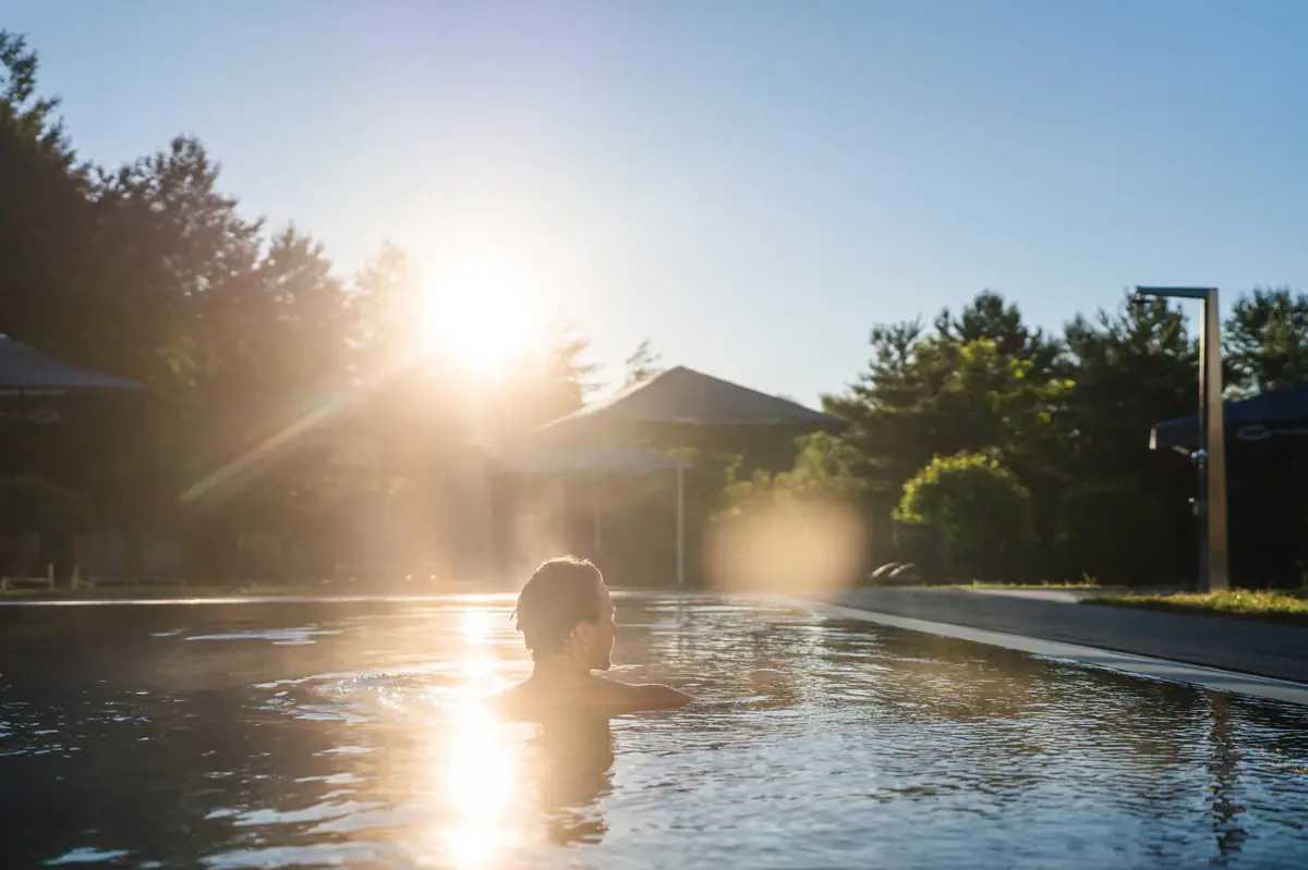 aja SPA Eine Person in einem Pool, auf dem die Sonne scheint.