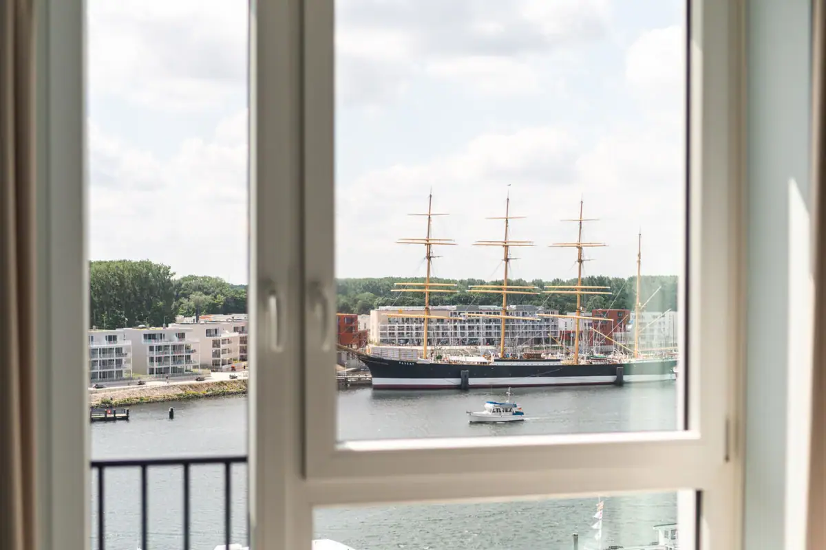 Zimmer mit Traveblick Blick aus einem Fenster auf ein Schiff und einen Hafen.