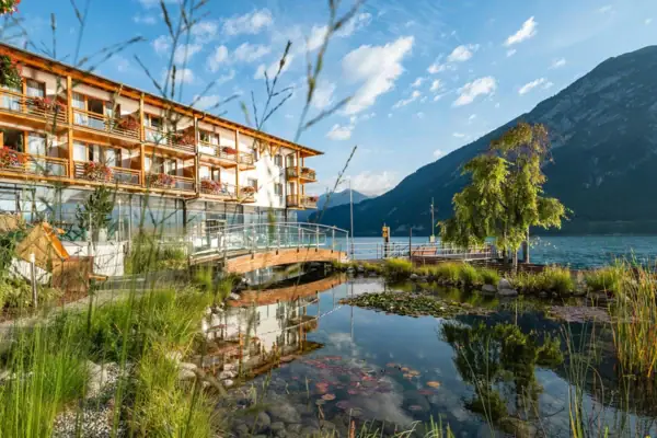 Ein Gebäude neben einem Gewässer mit Bäumen und Wolken am Himmel.