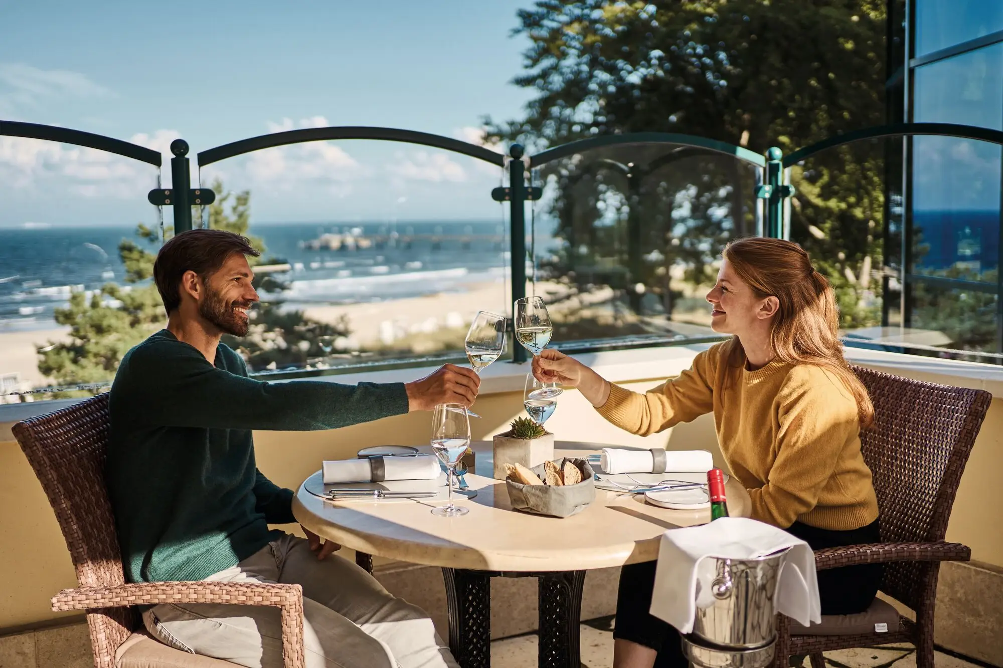 Terrasse im aja Bansin Restaurantinterieur mit Tischen und orangenen und grauen Stühlen und hellen Holzbalken an der Decke