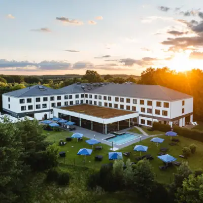 aja Bad Saarow Ein Gebäude mit einem Pool und Sonnenschirmen in der Mitte.