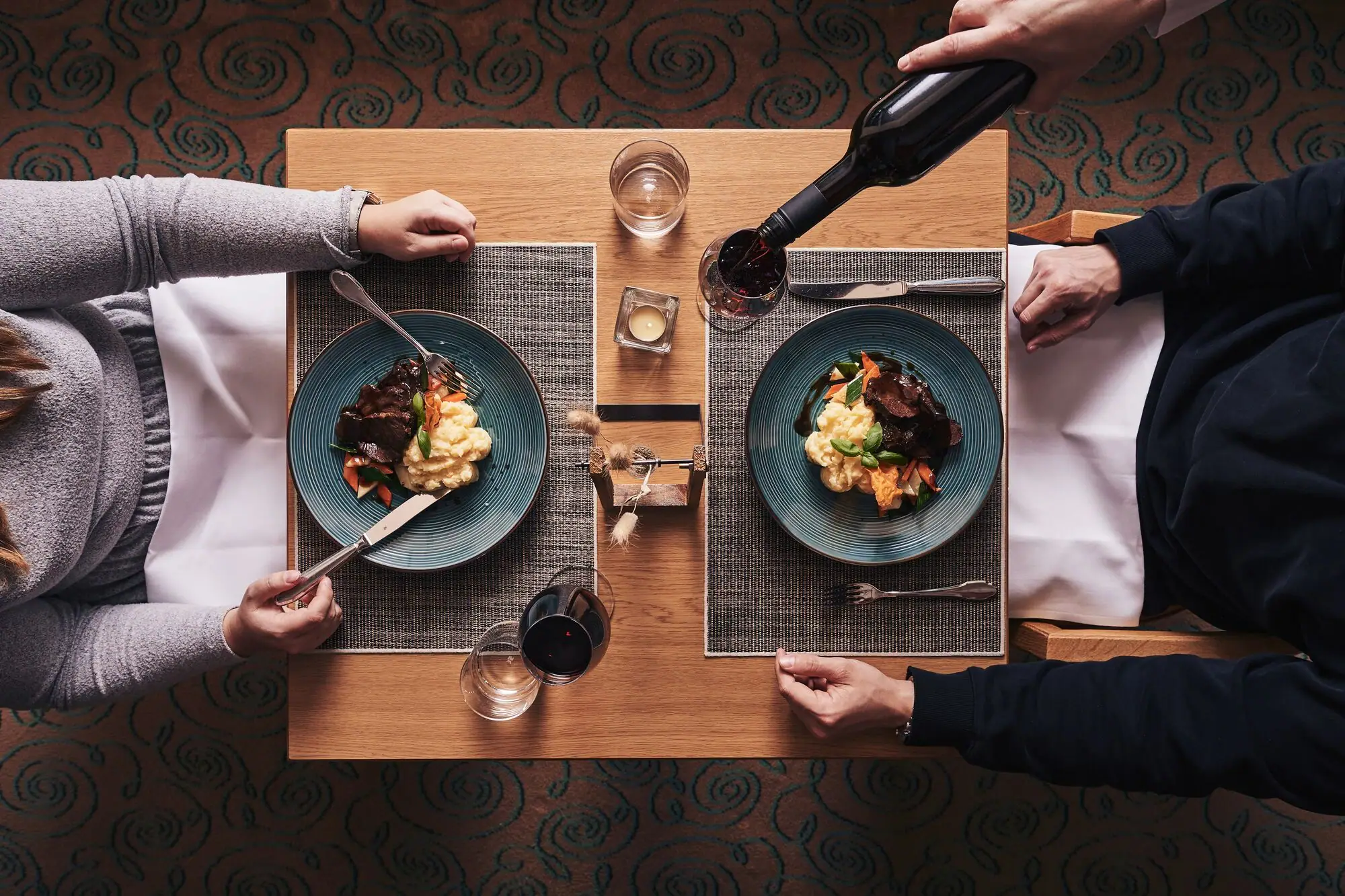 Restaurant Flora Eine Person hält eine Weinflasche und isst Essen.