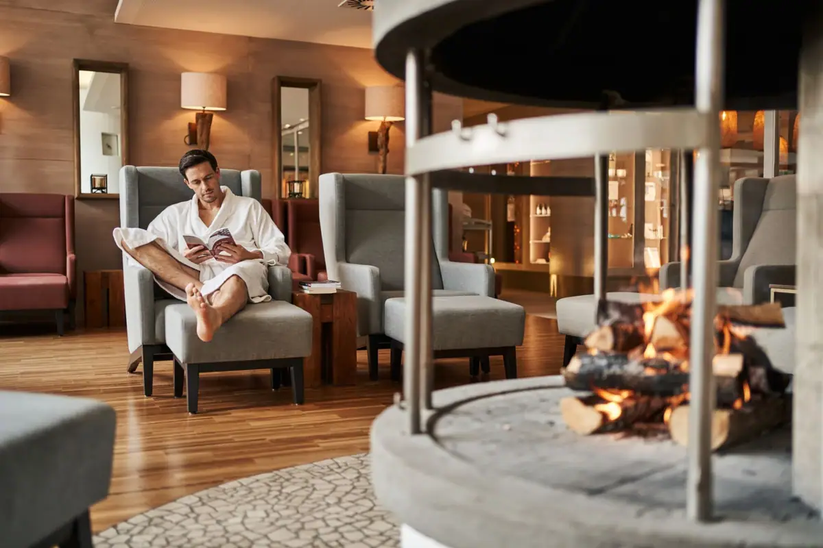 Kamin im SPA Ein Mann in einem Bademantel sitzt in einem Stuhl am Kamin.
