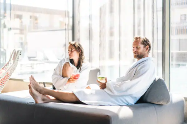 SPA Lounge Ein Mann und eine Frau in Bademänteln sitzen auf einem Sofa.