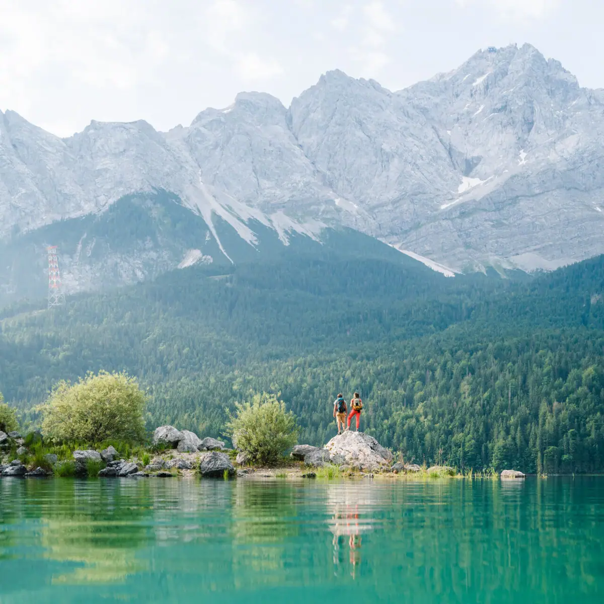 Eibsee Zwei Personen stehen auf einem Felsen vor einem Gewässer.