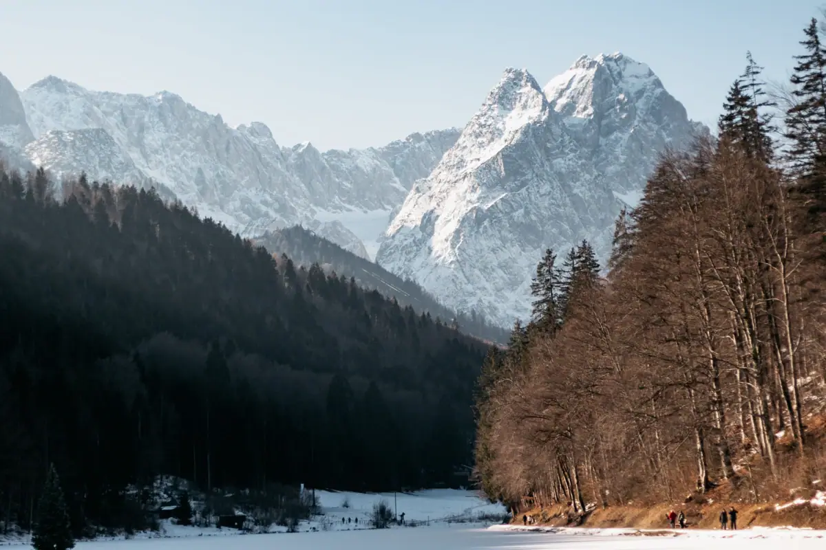 Winterlandschaft Ein See umgeben von Schnee und Bäumen.