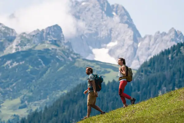 Wandern Garmisch Zwei Personen wandern auf einem Hügel mit Bergen im Hintergrund.