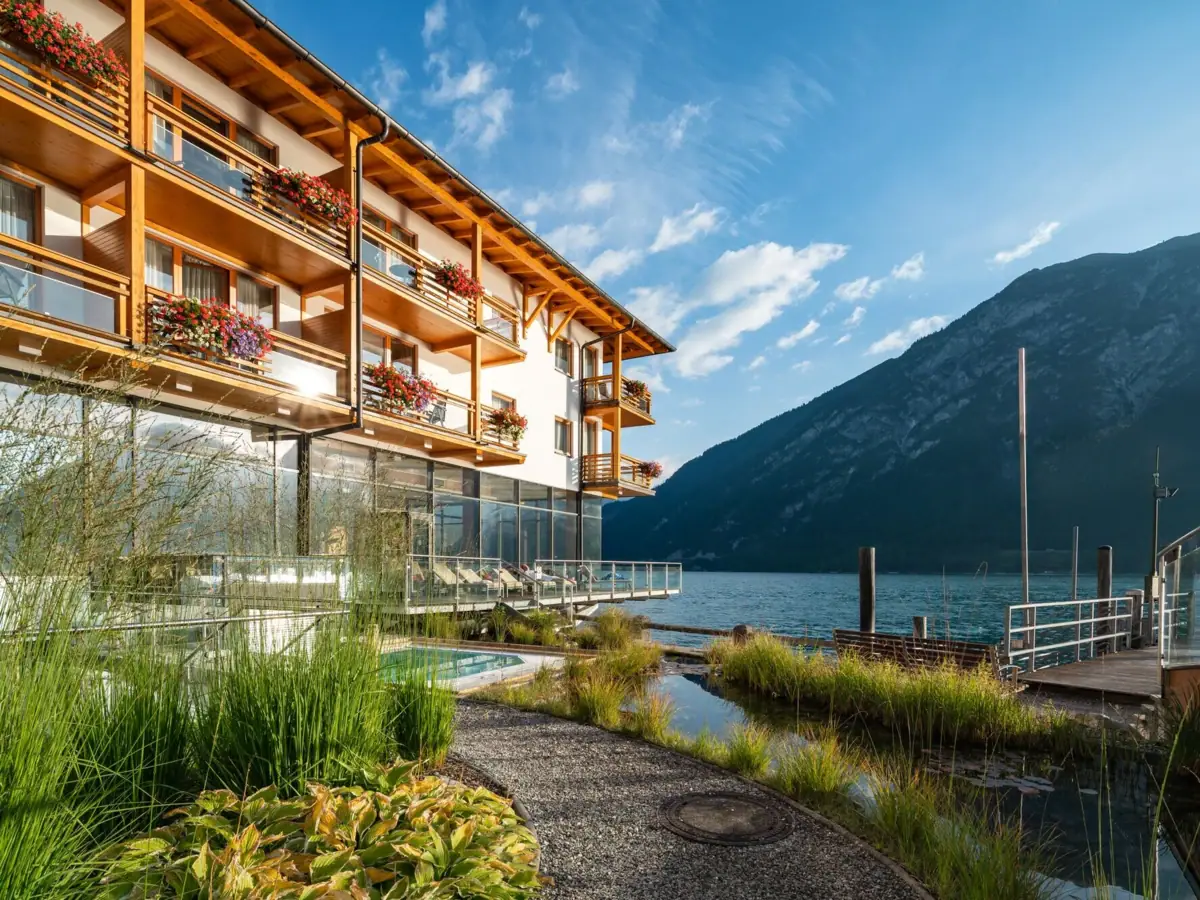 aja Fürstenhaus am Achensee Ein Gebäude mit einem See und Bergen im Hintergrund.
