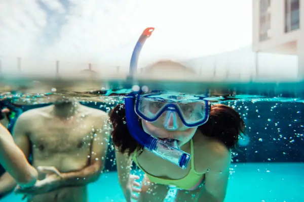 Eine Frau in einem Badeanzug und mit Schwimmbrille unter Wasser.