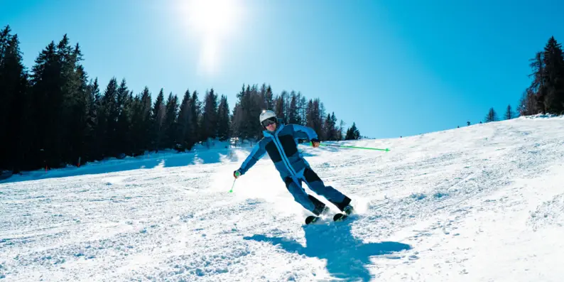 Ein blau gekleideter Skifahrer fährt an einem sonnigen tag einen schneebedeckten Hang hinunter. Ein blau gekleideter Skifahrer fährt an einem sonnigen tag einen schneebedeckten Hang hinunter.