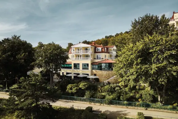 aja Bansin Außenansicht vom aja Bansin umgeben von grünen Bäumen an einem sonnigen Tag.