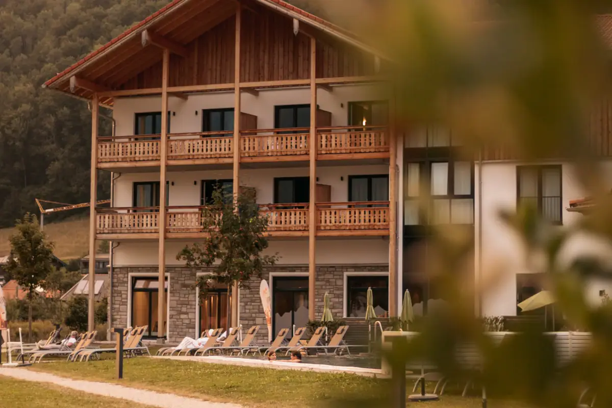 aja Ruhpolding Ein Gebäude mit Rasenstühlen und Bäumen im Hintergrund.