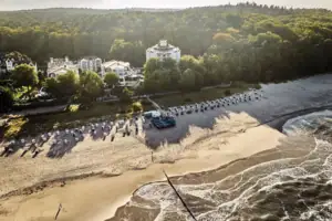 aja Strandhotel Bansin Ein Strand mit vielen Strankörben und Bäumen.