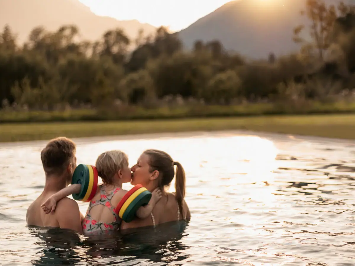 Familie im Pool Eine Gruppe von Menschen im Pool, ein Kind gibt einen Kuss.