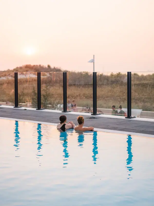 Außenpool im aja Warnemünde Zwei Personen schwimmen in einem Pool im Freien.