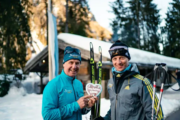 Biathlon-Training Zwei Männer halten Skier und lächeln.