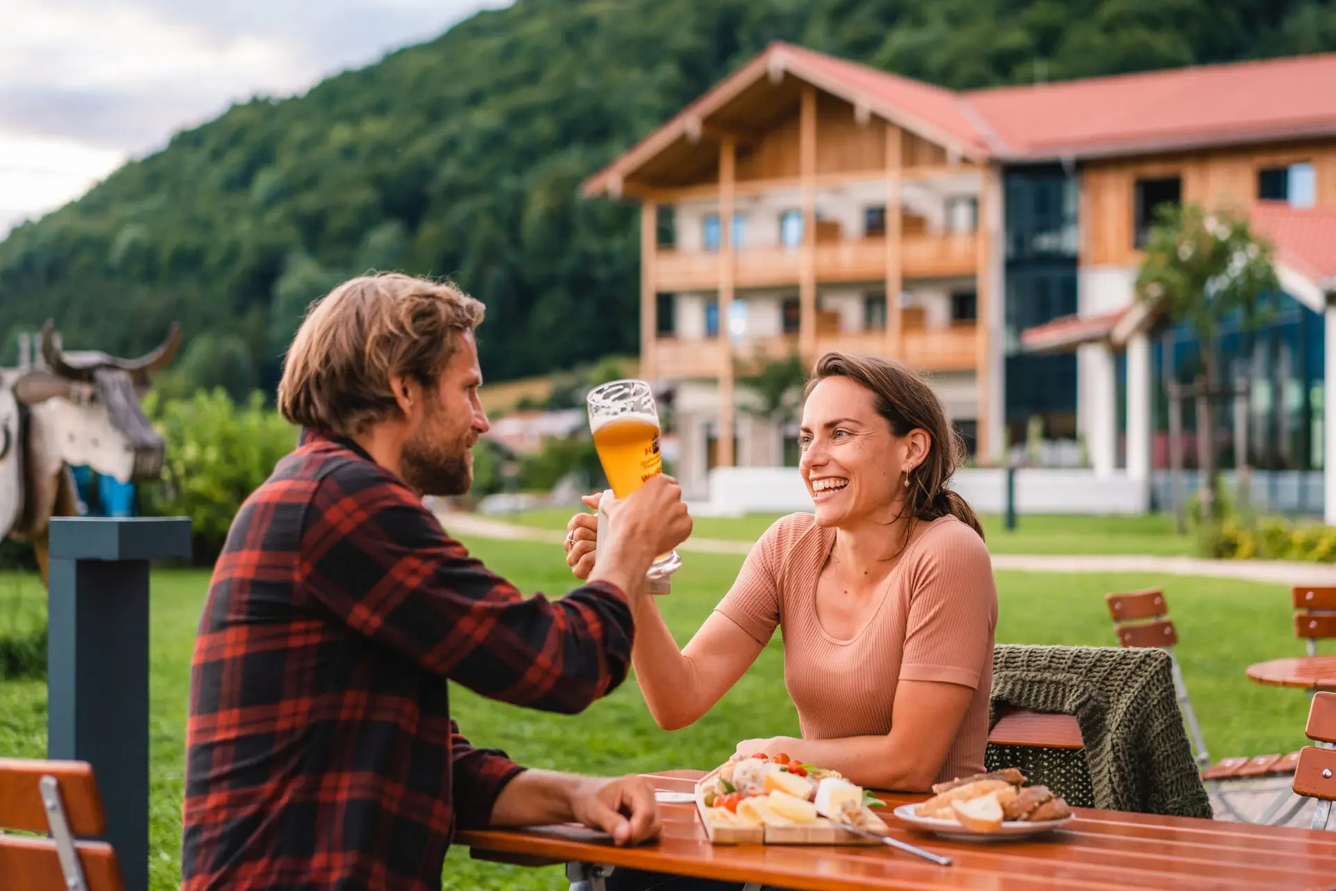 Biergarten Ein Mann und eine Frau sitzen an einem Tisch mit Essen und Getränken.