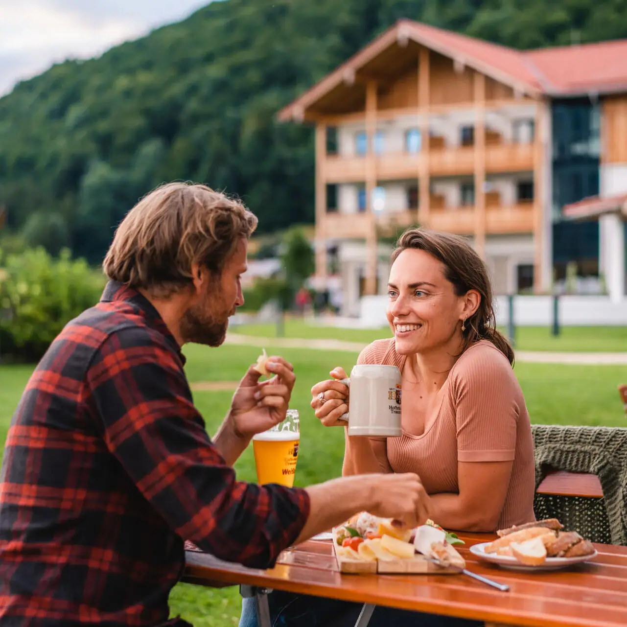 Biergarten aja Ruhpolding Ein Mann und eine Frau sitzen an einem Tisch mit Essen und Getränken.