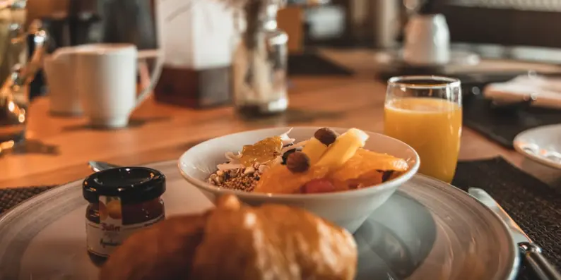 Eine Schüssel mit Müsli und Früchten auf einem Teller mit einem Croissant und Marmelade. Eine Schüssel mit Müsli und Früchten auf einem Teller mit einem Croissant und Marmelade.