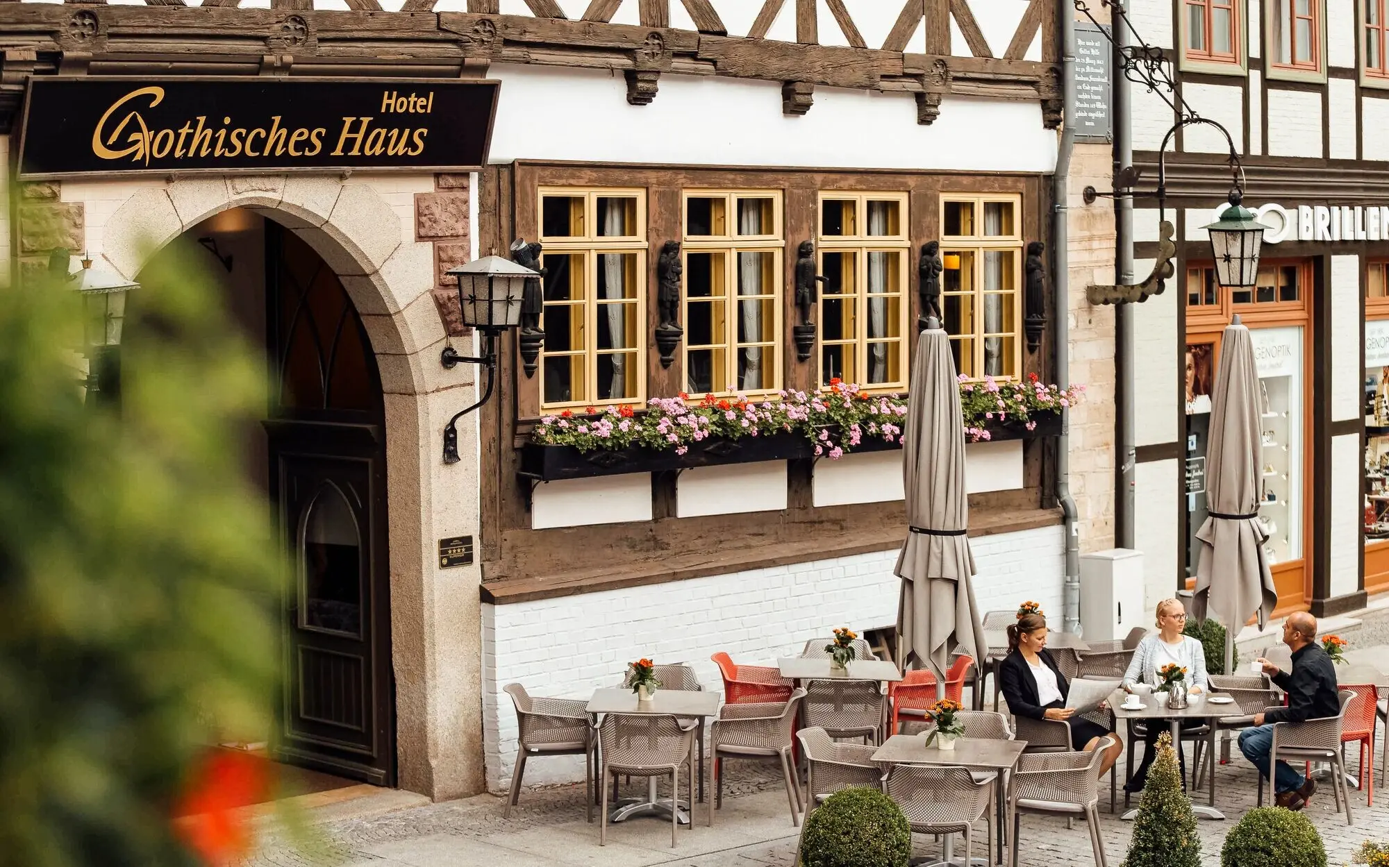 Gothisches Haus Wernigerode Gruppe von Personen sitzt an Tischen vor einem Gebäude.