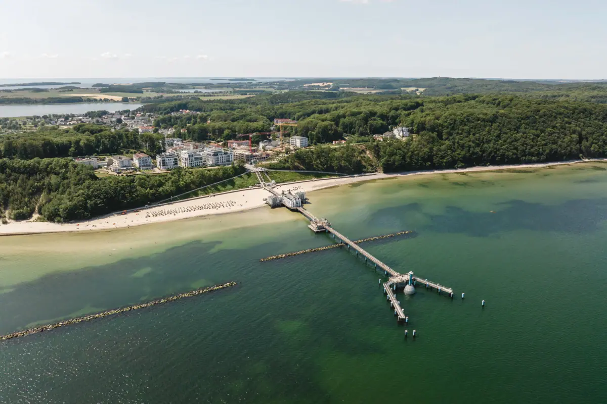 Rügen von oben Ein Steg an einem Strand mit Blick auf das Wasser und den Himmel.