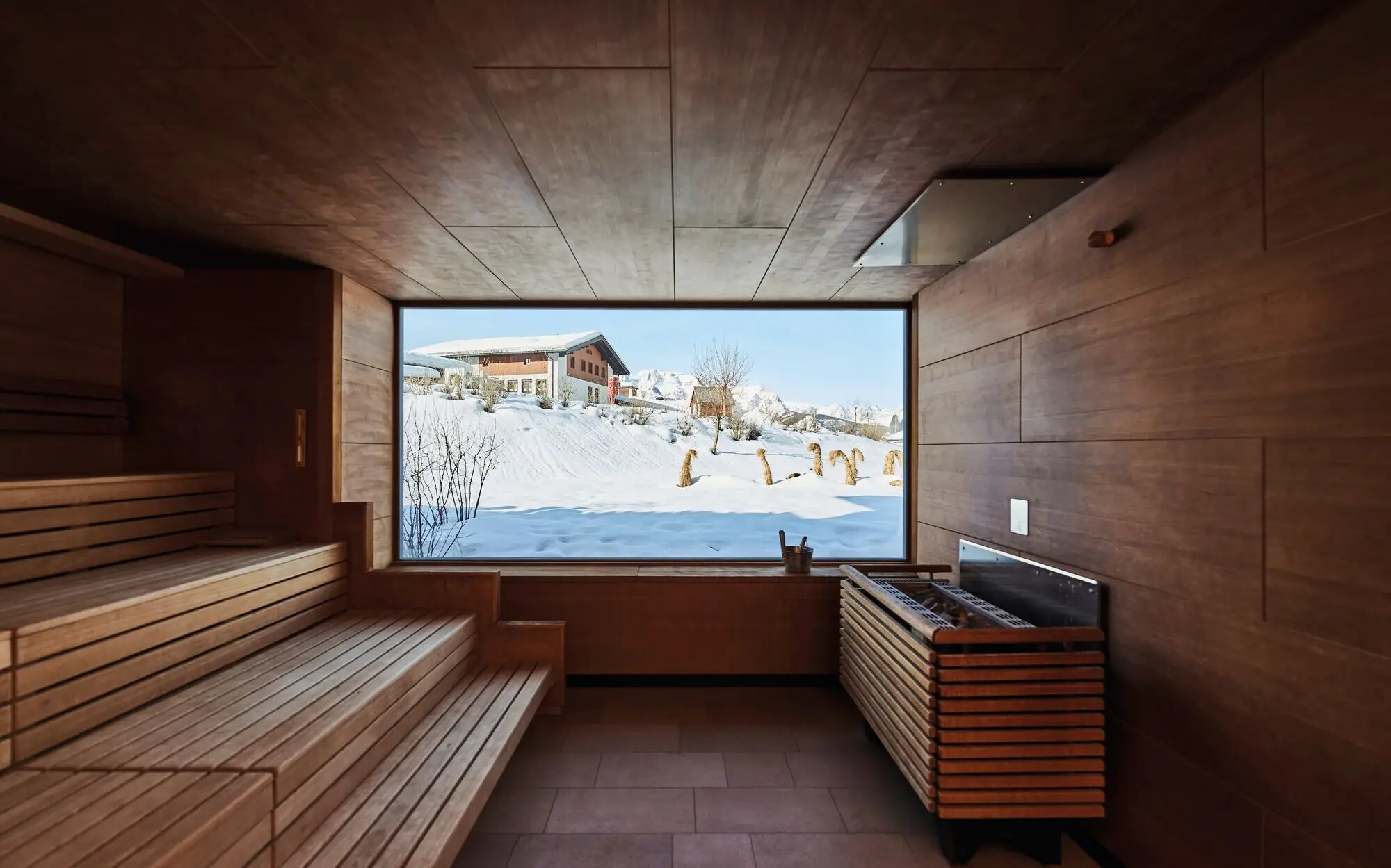 Sauna aja Werfenweng Holzsauna mit großem Fenster mit Blick auf schneebedeckte Umgebung.