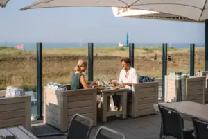 Terrasse Eine Gruppe von Menschen sitzt an einem Tisch im Freien.