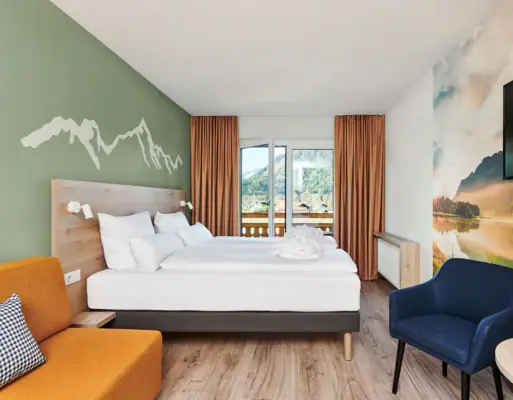 Doppelzimmer mit Balkon aja Ruhpolding Ein Zimmer mit einem Bett und einem Stuhl.