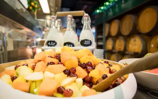 Nahaufnahme einer großen Schale Obstsalat mit Milchflaschen im Hintergrund. Nahaufnahme einer großen Schale Obstsalat mit Milchflaschen im Hintergrund.