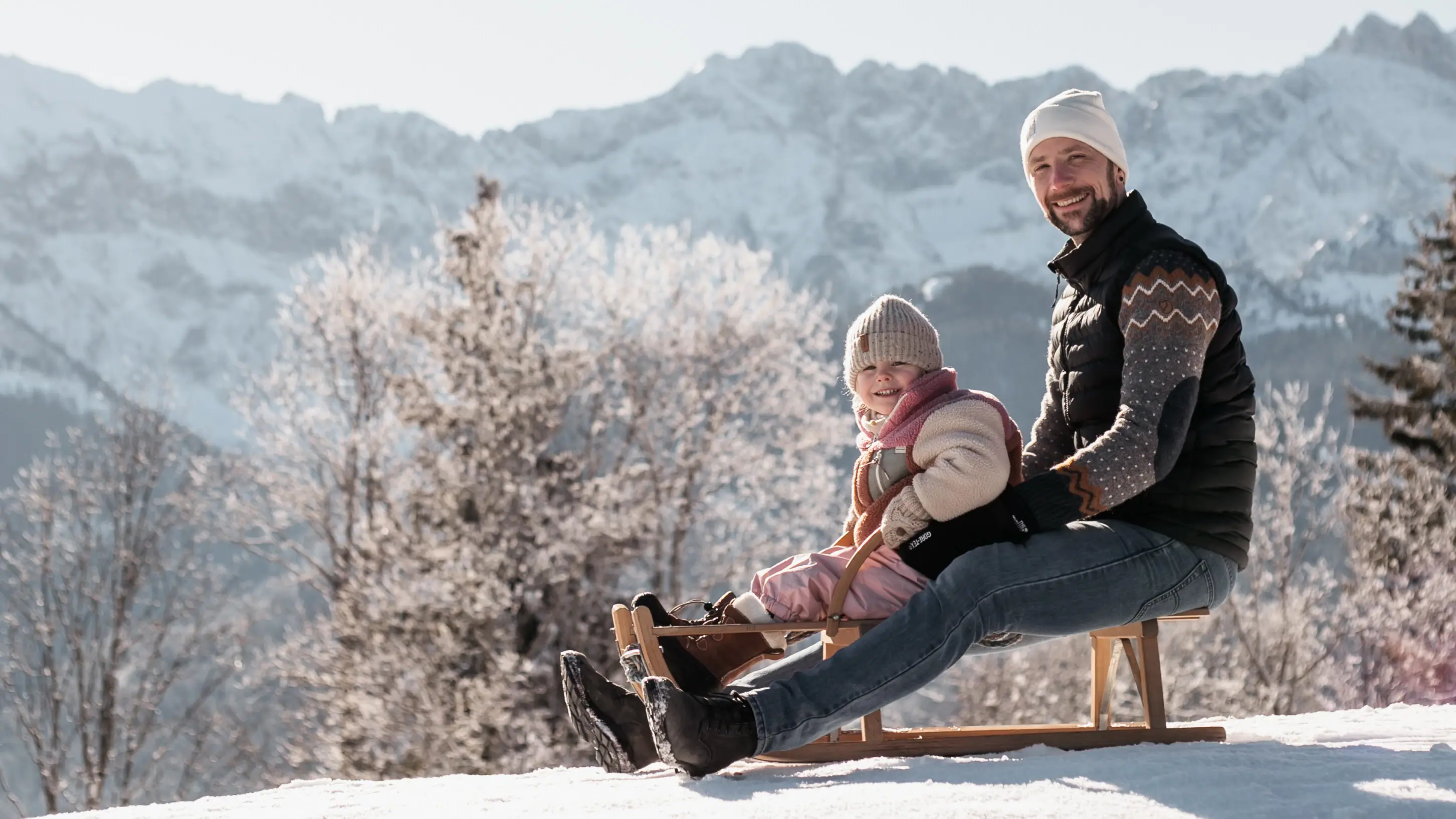 Schlittenfahren Ein Mann und ein Kind auf einem Schlitten im Schnee.