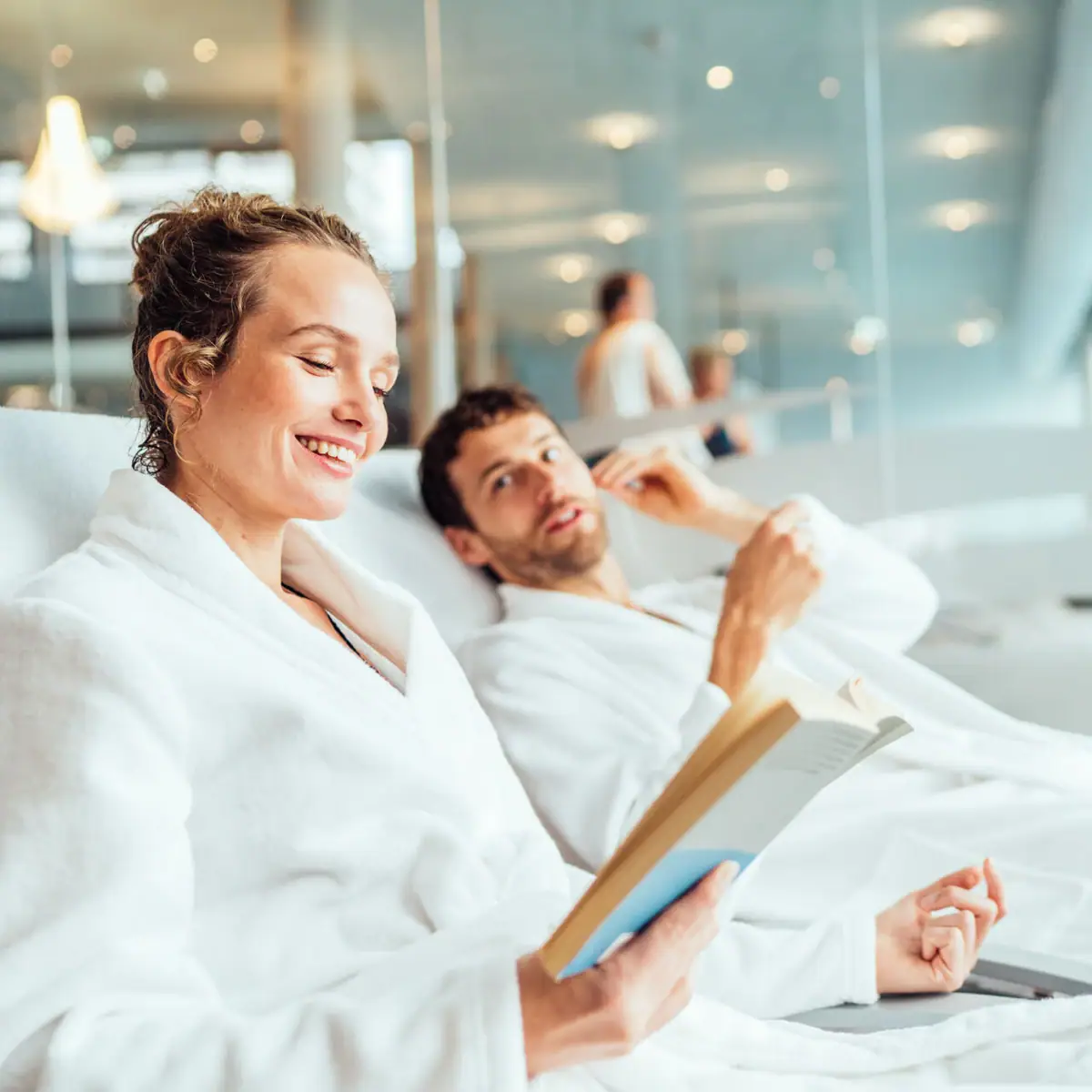 Entspannung im aja SPA Ein Mann und eine Frau in Bademänteln lesen ein Buch.