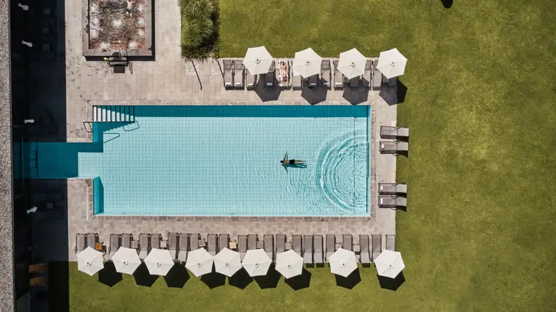 Pool von oben Schwimmbecken mit Sonnenschirmen und Rasen.