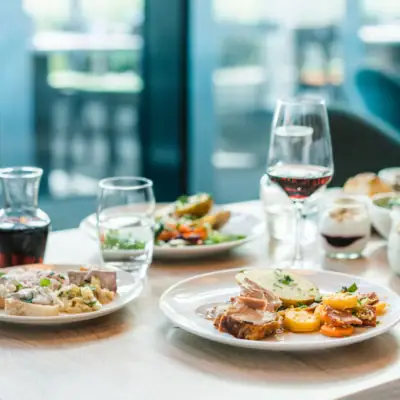 Abendessen Ein Tisch mit Tellern voller Speisen und Weingläsern.