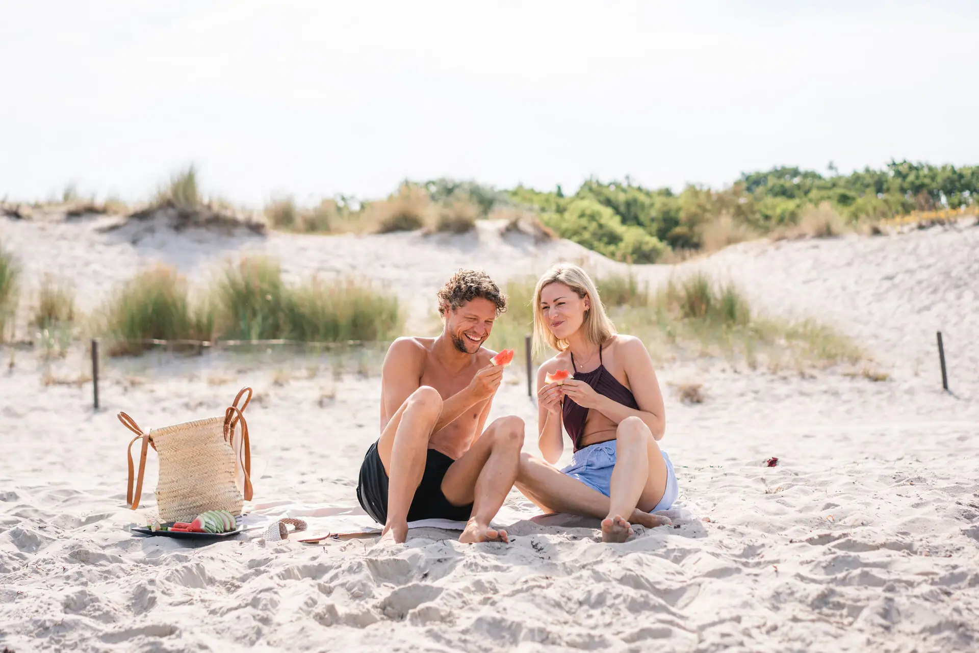 Warnemünde Strand Ein Mann und eine Frau sitzen am Strand und essen Wassermelone.
