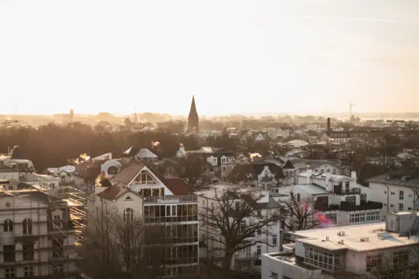 Blick über Warnemünde Stadt mit vielen Gebäuden und klarem Himmel im Hintergrund.