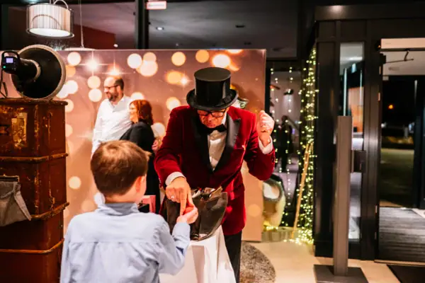 Silvester im aja Travemünde Ein Mann im roten Anzug übergibt einen geknoteten Ballon einem Jungen.