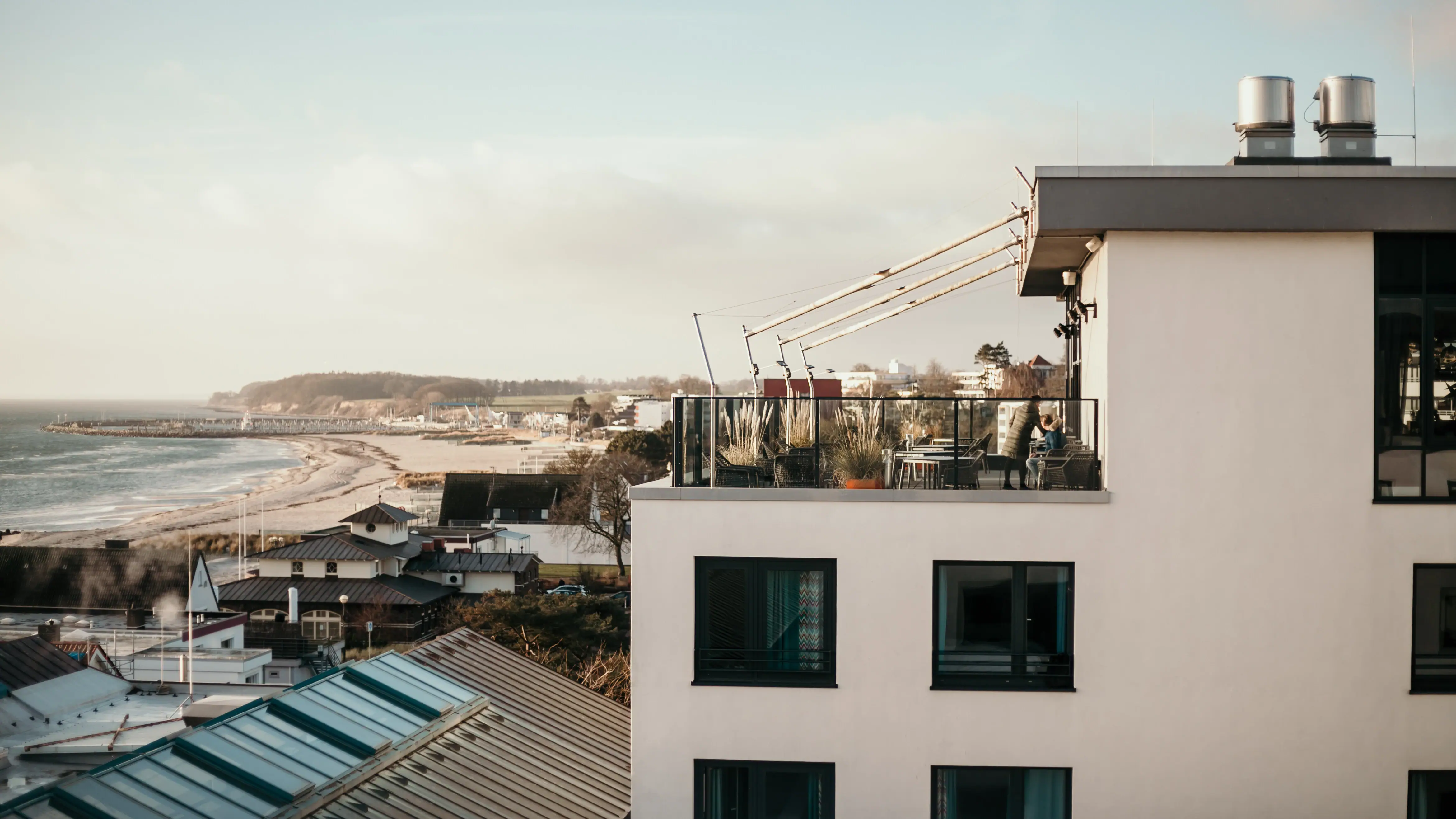 aja Grömitz Ein Gebäude mit einem Balkon, der auf ein Gewässer blickt.
