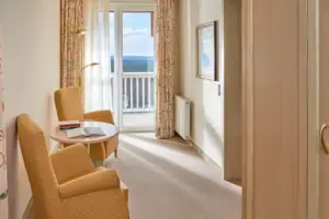 Juniorsuite seeseitig mit Balkon Ein Zimmer mit einem Tisch und Stühlen.