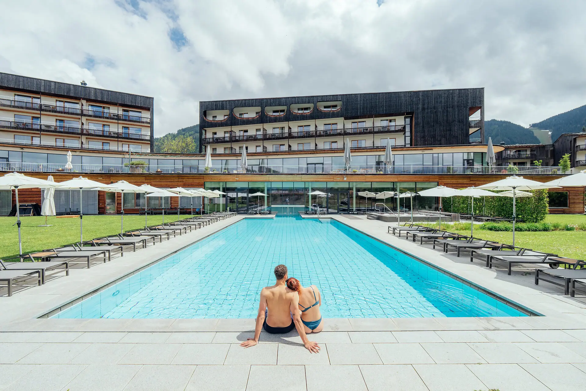 Außenpool Ein Mann und eine Frau sitzen an einem Pool.