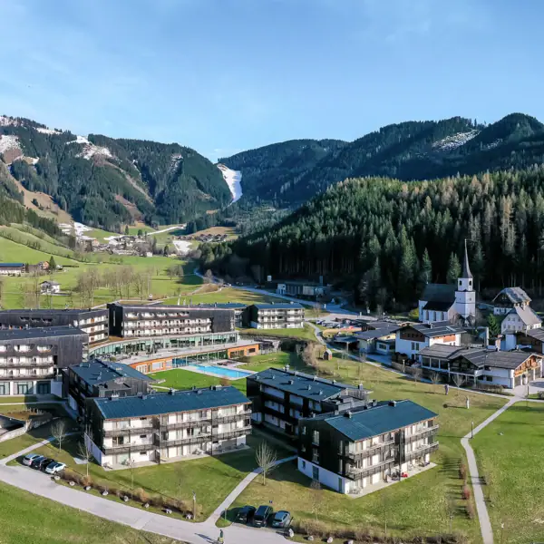 Bergresort Werfenweng Eine Gruppe von Gebäuden in einem Dorf vor einem Berg.
