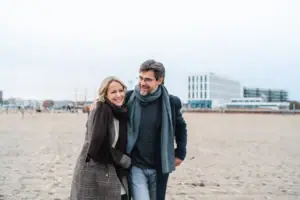 Ausblick Ein Mann und eine Frau spazieren am Strand entlang.