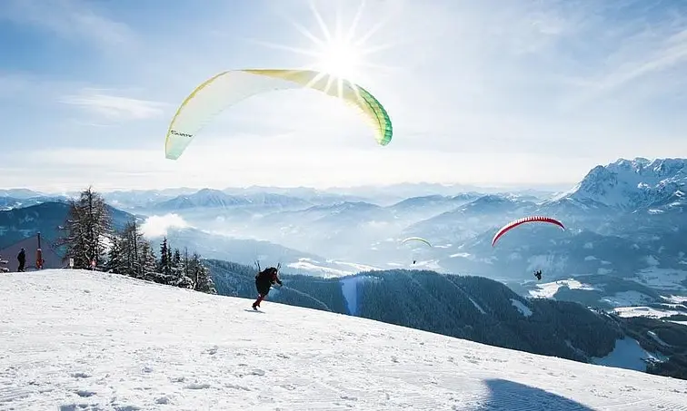Paragliding Gruppe von Personen beim Paragliding auf einem verschneiten Berg.