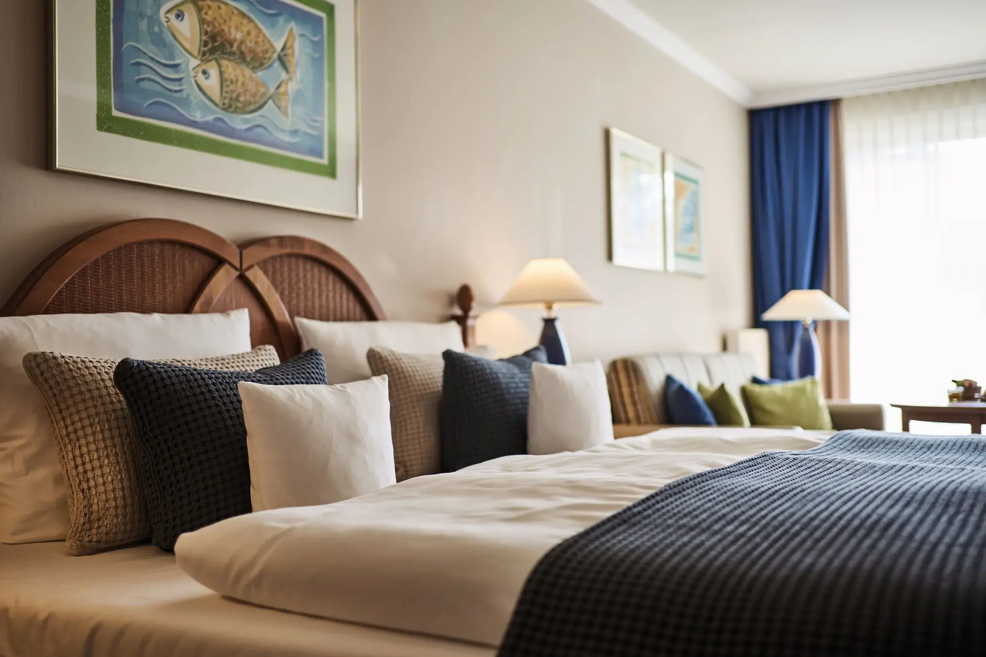 Zimmer im aja Bansin Ein Bett mit Kissen und Lampen in einem Zimmer.